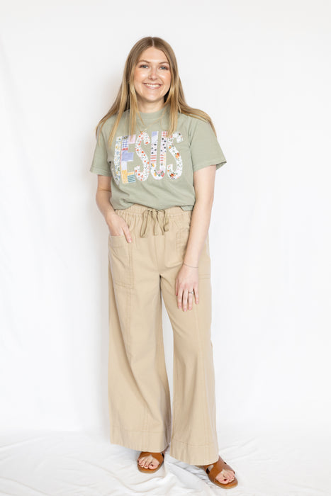 Woman wearing a t-shirt with colorful text and beige pants 