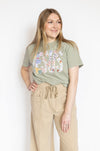 Woman wearing a green t-shirt with embroidered Jesus text and beige pants 
