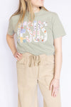 Woman wearing a green t-shirt with embroidered Jesus text and beige pants 