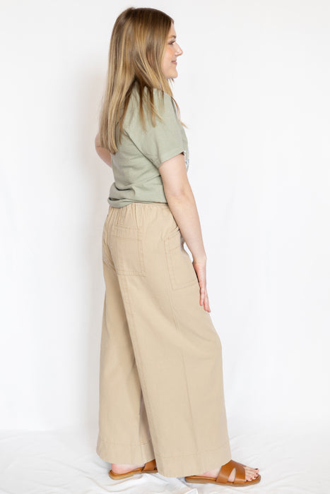 Woman wearing a green t-shirt with embroidered Jesus text and beige pants 