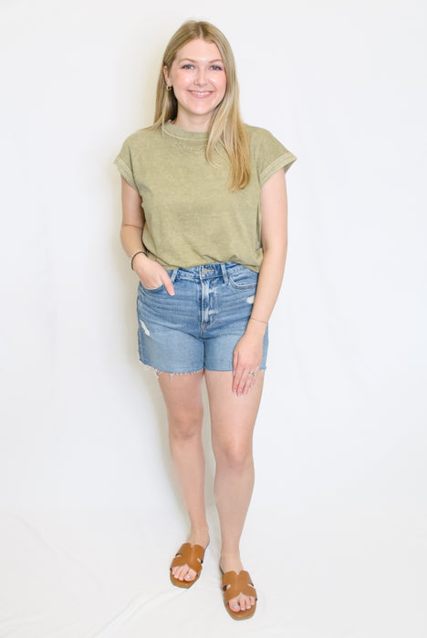 Woman wearing a green top and blue shorts 