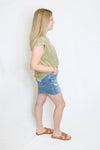 Woman wearing a green t-shirt and denim shorts 