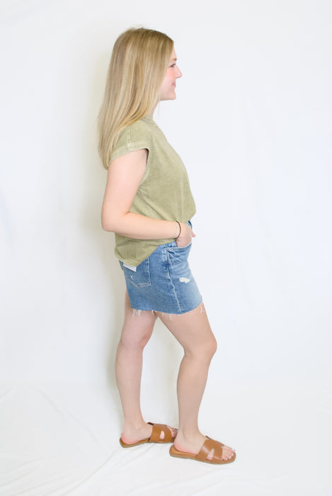 Woman wearing a green t-shirt and denim shorts 