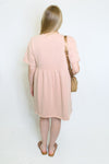 Woman wearing a pink dress holding a beige handbag 
