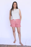Woman wearing a white sleeveless top and red checkered shorts 