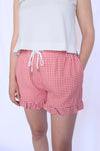Person wearing red gingham shorts with a white 