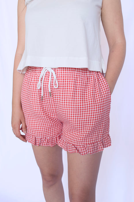 Person wearing red gingham shorts with a white 