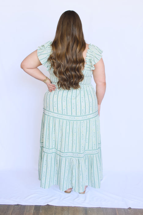 Woman wearing a green dress with ruffled sleeves and striped pattern