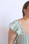 Woman wearing a green and white patterned dress with ruffled sleeves 