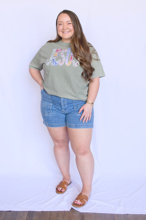Woman wearing a green t-shirt with colorful graphics and denim shorts 