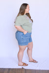 Woman wearing a green t-shirt and blue denim shorts 
