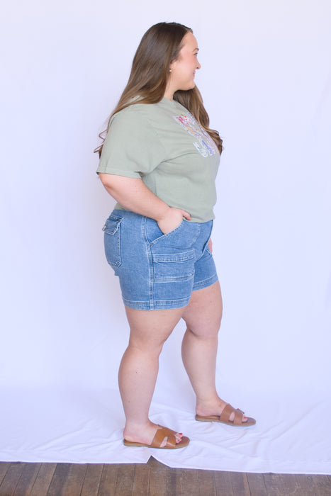 Woman wearing a green t-shirt and blue denim shorts 