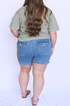 Person wearing a green t-shirt and blue denim shorts 