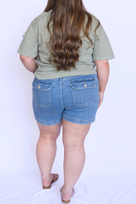 Person wearing a green t-shirt and blue denim shorts 