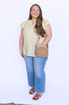 Woman wearing a light yellow blouse, blue jeans, and carrying a beige handbag 