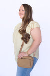 Woman holding a brown crossbody bag 