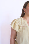 Woman wearing a light yellow blouse with ruffled sleeves 