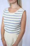 Woman wearing a sleeveless top with blue and white striped pattern 