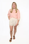 Woman wearing a pink striped shirt and beige shorts 