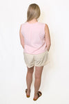 Person wearing a light pink sleeveless top and beige shorts 