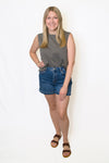 Woman wearing a gray sleeveless top and blue denim shorts 