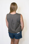 Person wearing a gray sleeveless top and blue shorts 