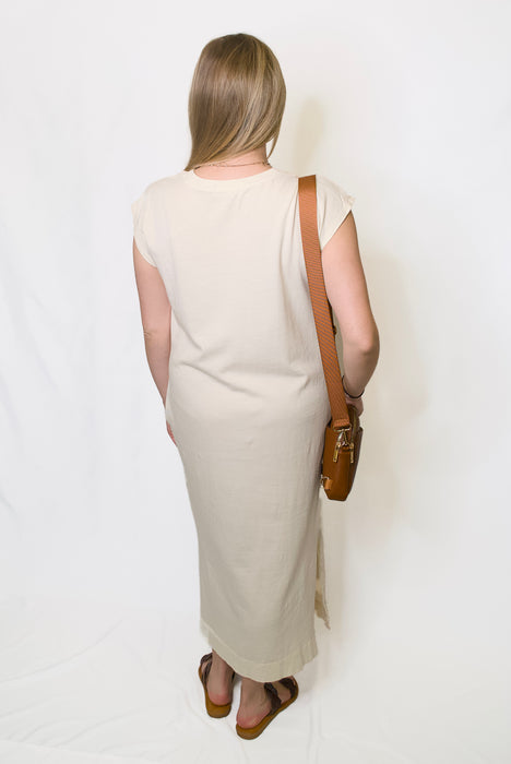 Woman wearing a beige dress with a brown bag