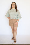 Person wearing a light blouse and beige shorts 