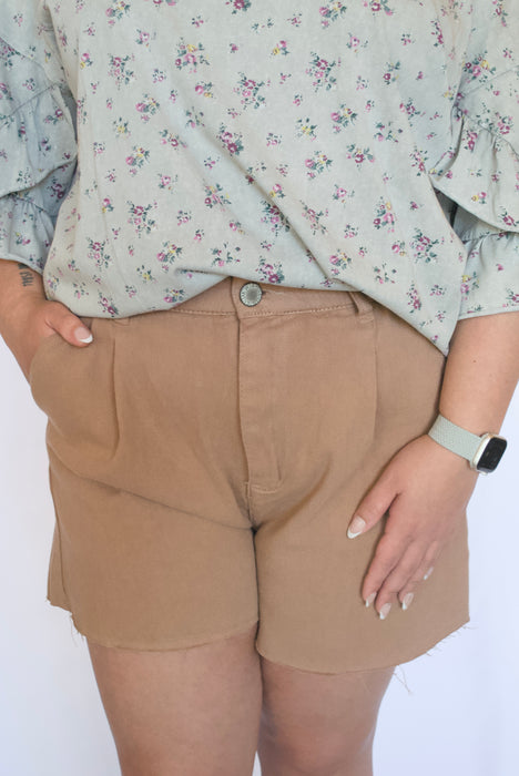 Person wearing beige shorts and a floral blouse