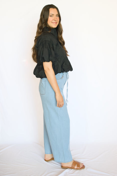 Woman wearing a black top and light blue pants 