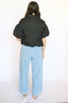 Person wearing a black top and light blue pants 