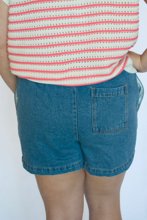Person wearing a striped shirt and denim shorts 