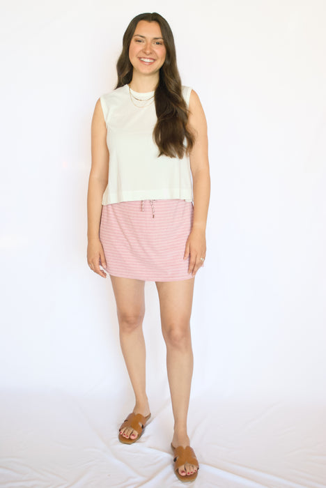 Woman wearing a white sleeveless top and pink checkered skirt 
