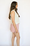 Woman wearing a white sleeveless top and pink checkered skirt 