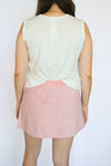 Person wearing a white sleeveless top and pink striped skirt 