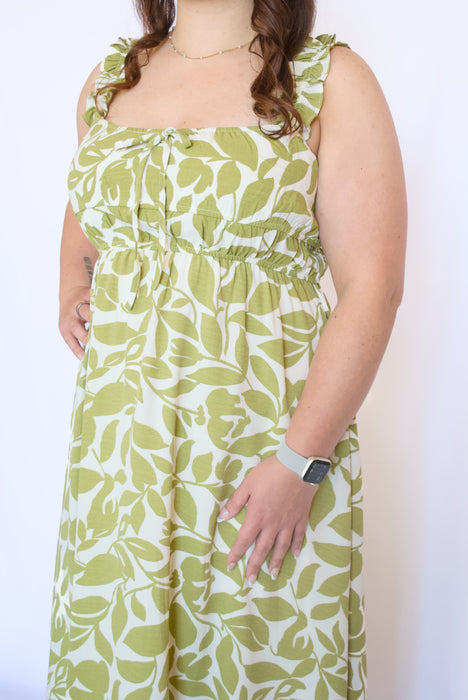 Woman wearing a sleeveless dress with green leaf pattern 