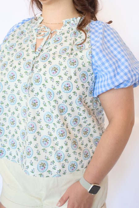 Woman wearing a floral blouse with blue checkered sleeves 