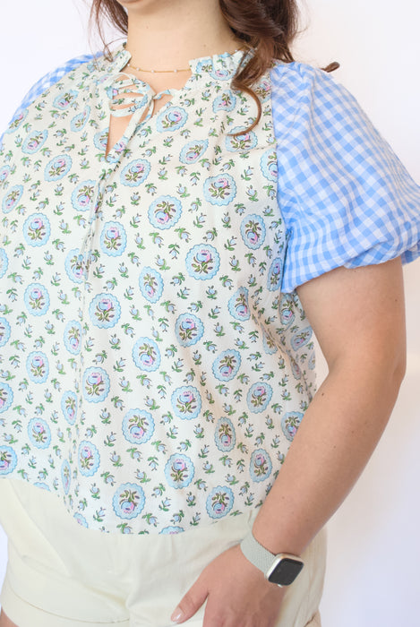 Woman wearing a floral blouse with blue checkered sleeves 