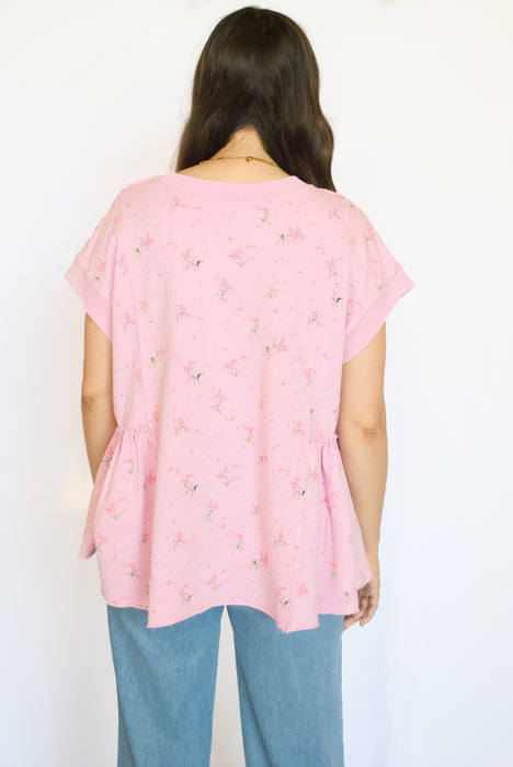 Person wearing a pink floral top and blue jeans 