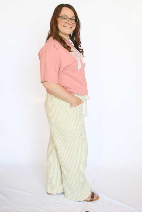 Woman wearing a pink shirt and white striped pants 