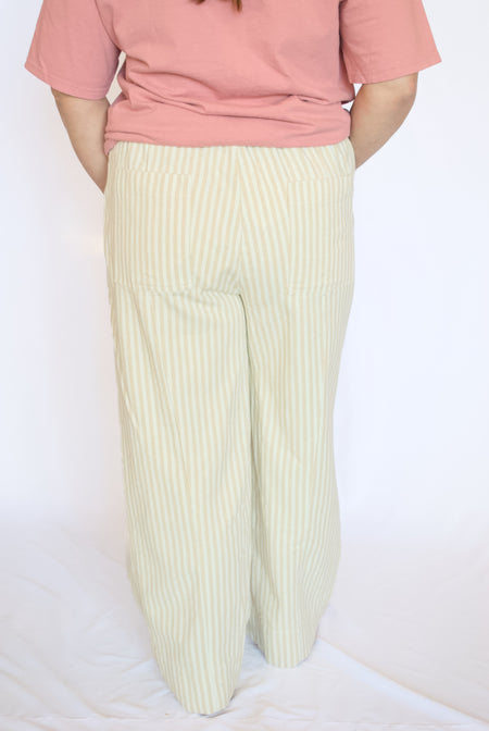 Person wearing a pink top and white striped pants 