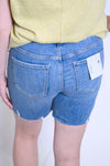 Person wearing blue denim shorts with a yellow top 