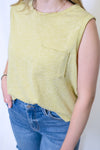Person wearing a yellow sleeveless top with a pocket and blue jean shorts