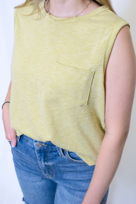 Person wearing a yellow sleeveless top with a pocket and blue jean shorts