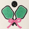 Embroidered design of two green ping pong paddles with a pink bow and a black ball 